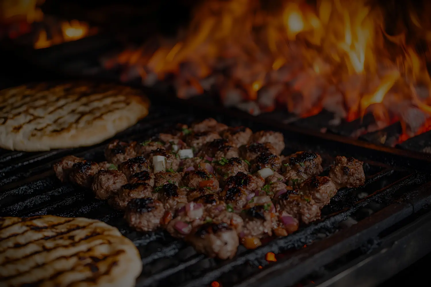 Saftige Fleischspieße mit Kräutern und Zwiebeln brutzeln neben Fladenbrot am Grill